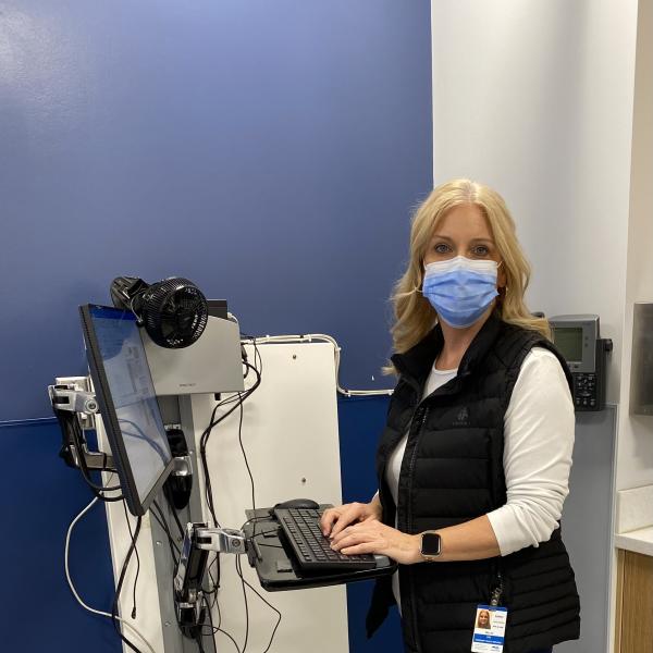 Woman with blonde hair in scrubs working with medical equipment.